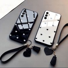 two cell phones sitting next to each other on top of a table with black and white accessories