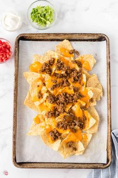 nachos with cheese and ground beef on a baking sheet