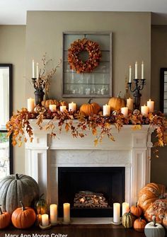 a mantel with candles, pumpkins and other autumn decorations on top of it