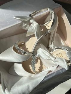 a pair of white wedding shoes with bows on the toes and heels are sitting in a box