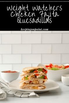 a stack of quesadillas sitting on top of a white plate next to a bowl of salsa