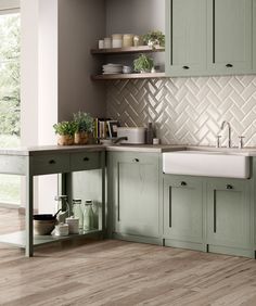 a kitchen with green cupboards and white tile backsplash, wood flooring