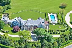 an aerial view of a large mansion with a pool in the center and lush green trees surrounding it