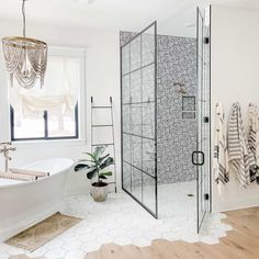 a bathroom with a glass shower door and white bathtub next to a wooden floor