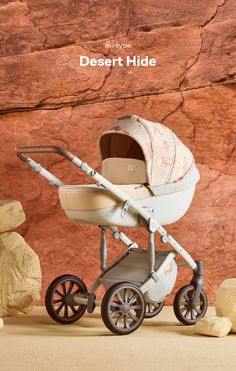 a baby stroller sitting in front of a rock wall with the words desert hide written on it