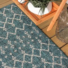 a blue and white rug sitting on top of a wooden floor next to a potted plant