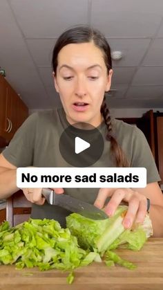 a woman cutting up lettuce on top of a wooden table