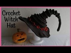 a crocheted hat is sitting next to a jack - o'- lantern