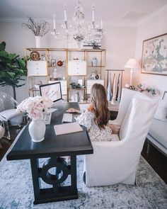 a woman sitting on a chair in front of a desk with a laptop and flowers