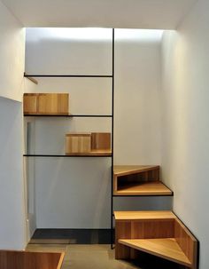 a set of wooden stairs leading up to a white wall with shelves on each side