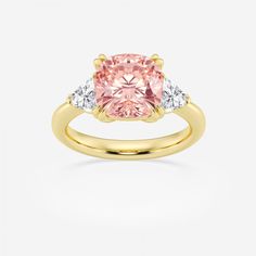 an engagement ring with a pink diamond and two white diamonds on the side, set in yellow gold