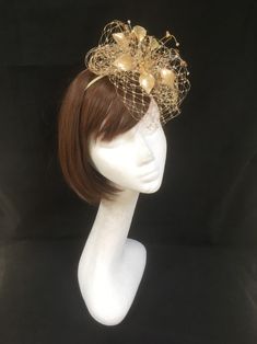 Delicate gold fascinator perfect for the guest who wants something fairly understated. This design is a beautiful selection of glass effect leaves and flowers with an additional scatter of brown crystal and tan glacier stone, clustered together amongst a fine layer of veiling and set onto a fine comfort base tiara band. As with all our designs, this piece can be made exact to the image or in any colour combination to match in with your outfit. If a specific colour is required customers can messa Elegant Headpiece With Structured Crown For Events, Gold Gatsby Style Formal Headpieces, Royal Ascot Headband Fascinator For Event, Royal Ascot Headband Fascinator, Royal Ascot Event Headband Fascinator, Gold Gatsby Headpiece For Party, Gold Gatsby Headpieces For Evening, Gold Gatsby Evening Headpieces, Gold Hat With Structured Crown For Party