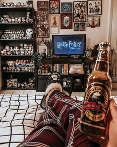 someone is laying on the bed with their feet up in front of a harry potter bottle