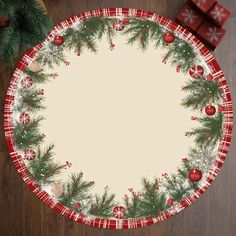 a christmas themed placemat with pine branches and red balls on it, surrounded by presents