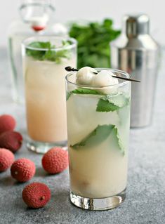 two glasses filled with ice and some raspberries on the table next to each other