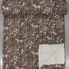 a brown and white quilted material with an intricate design on the front, along with a piece of fabric in the middle