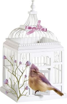 a bird in a white cage with pink flowers and a bow on it's head