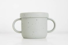 a white ceramic cup with black speckles on the outside and inside, sitting on a white surface