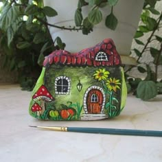 a small green house sitting on top of a table next to a pencil and potted plant