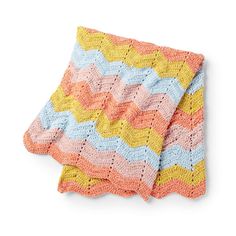 a crocheted blanket is laying on top of a white surface and it has an orange, yellow, blue, and pink chevron pattern