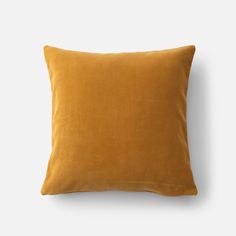 a mustard colored pillow on a white background