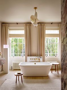 a bathroom with a large bathtub and two stools in front of the window