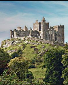 an old castle sitting on top of a lush green hillside