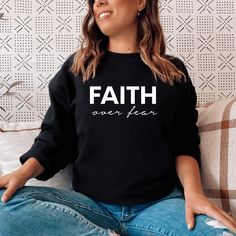 Keep warm and comfortable in this Faith Over Fear Sweatshirt. This cool Christian sweatshirt is soft, stylish, and sure to keep you warm in the colder months. It's versatile to wear for a day outdoors, heading to the gym, or a lazy day watching movies on the couch. Wearing Christian hoodies and sweatshirts can be a subtle way to express your faith and create conversations with anyone and be a gentle reminder to encourage you in any season. They can also spread encouraging words of faith everywhe Black Fleece Sweater With Letter Print, Black Relaxed Fit Comfortable Sweater, Comfortable Black Winter Tops, Black Comfortable Relaxed Fit Sweater, Black Comfy Sweats For Fall, Black Letter Print Sweats For Winter, Winter Letter Print Black Sweats, Winter Black Letter Print Sweats, Black Letter Print Sweatshirt For Leisure