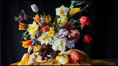 a vase filled with lots of colorful flowers on top of a yellow cloth covered table