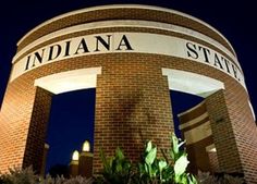 the indiana state university sign is lit up at night with trees and bushes around it