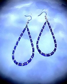 These beautiful 2 3/4" earrings are made with blue and purple and silver seed beads. These beads are a nice embellishment to the classic teardrop hoop earrings. These teardrop earrings are very comfortable because they are so lightweight.  Hoop earrings are classic, and these are teardrop hoops, with a pattern that makes a statement. You can't go wrong with these earrings! They are great all year round. These would be great on to wear on July fourth! They come in a box for easy gift giving too. Blue Teardrop Hoop Earrings With Dangling Beads, Silver Teardrop Jewelry With Tiny Beads, Blue Beaded Hoop Earrings Gift, Gift Blue Beaded Hoop Earrings, Silver Teardrop Beaded Earrings, Blue Teardrop Jewelry With Silver Beads, Blue Hoop Earrings With Dangling Beads Gift, Handmade Blue Teardrop Hoop Earrings, Blue Beaded Long Drop Jewelry