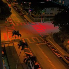 an aerial view of a city street at night with palm trees and buildings in the background