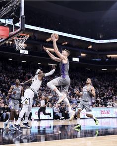 a group of men playing basketball against each other on a court in front of an audience