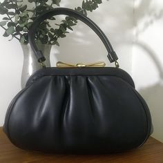 "1960s Granada USA Black Soft Vinyl Leather Top Handle Handbag, Vintage 60s Purse Classy 1960s Granada USA black soft vinyl leather top handle handbag that features: Gold tone metal hardware with a really pretty gold tone metal bow clasp closure that works well and closes tightly. Opens to a black satin lining with one interior side open pocket and one interior side metal zippered pocket. Stamped Granada USA There are protective feet on the bottom of the bag. Nearest mint condition *the exterior Formal Black Satchel With Rolled Handles, Black Satchel With Rolled Handles For Formal Events, Black Satchel With Rolled Handles For Formal Occasions, Black Retro Handheld Satchel, Retro Black Handheld Satchel, Evening Satchel With Rolled Handles, Retro Leather Shoulder Bag For Party, Vintage Bags With Detachable Handle, Retro Black Clutch Shoulder Bag