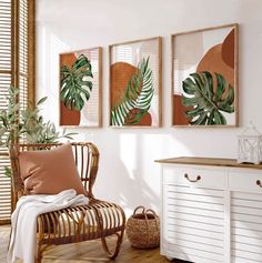 a room with three paintings on the wall and a wicker chair in front of it