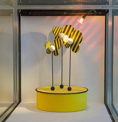 a display case with three yellow and black striped flowers in the shape of bee's