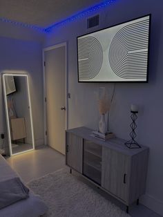 a bedroom with a bed, mirror and television mounted on the wall in front of it