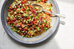 a bowl filled with lots of vegetables on top of a white tablecloth next to a spoon