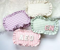 four gingham pillows with the letters on each one and an embroidered pillow in the middle