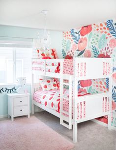 a white bunk bed sitting in a bedroom next to a pink and green wallpaper