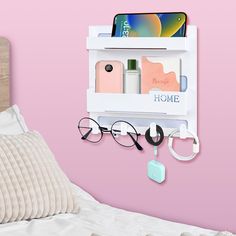 an eyeglass holder is hanging on the wall next to a bed with pink walls