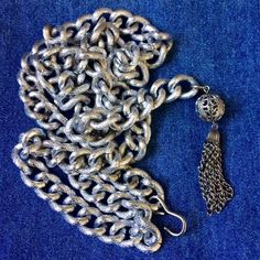 Well made lightweight aluminum chain belt/necklace. Textured silver tone links measure approx. 1/2 inch by 3/4 inch. Chain measures approx. 35 inches long with a 2 3/4 inch filigree ball and tassel on one side, j hook on other side. Fully adjustable. Can be worn a number of ways.Condition is very good vintage. As found. I leave decision of cleaning up to buyer. Silver Lariat Necklace With Chunky Chain, Vintage Silver Adjustable Chain Belt, Vintage Silver Chain Belt For Party, Silver Adjustable Chain Belt For Evening, Silver Chain Link Necklace For Parties, Silver Chain Strap Belt For Evening, Silver Adjustable Chain Necklace For Evening, Silver Long Chain Necklace For Evening, Silver Long Necklace For Evening