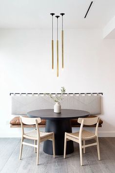 a dining room table with four chairs and a vase on the table in front of it