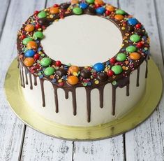 a white cake with chocolate and candy toppings on the top is sitting on a gold plate