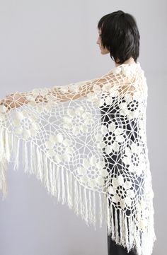 a woman wearing a white crochet shawl with flowers on the side and fringe