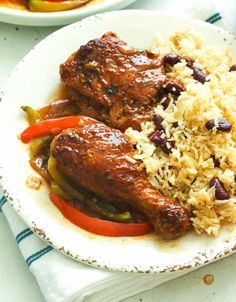 a white plate topped with rice and meat covered in sauce next to a bowl of vegetables