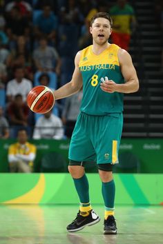 a man holding a basketball in his right hand and wearing green shorts with yellow trim