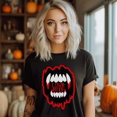 "🎃🦇 Get ready to sink your teeth into the Halloween spirit with our bold and playful \"Love Bite\" t-shirt. This isn't just any ordinary t-shirt - it's your ticket to effortless style and comfort during the most bewitching time of the year. Whether you're hitting up haunted houses, attending costume parties, or just enjoying the crisp autumn air, this t-shirt is the perfect addition to your spooky wardrobe. Featuring a bold and eye-catching design of large vampire teeth forming the words \"Lov Halloween Concert T-shirt With Crew Neck, Edgy Halloween T-shirt With Screen Print, Edgy Halloween T-shirt For Alternative Fashion, Halloween Concert Crew Neck T-shirt, Halloween Crew Neck T-shirt For Concert, Alternative Halloween T-shirt With Letter Print, Edgy Halloween Graphic Tops, Edgy Halloween Concert T-shirt, Black Halloween Concert T-shirt