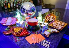 a table topped with plates and bowls filled with food next to a disco ball on top of a bar