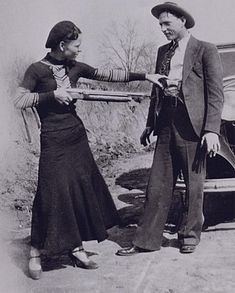 an old black and white photo of two people in front of a car talking to each other